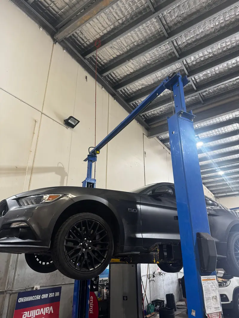 Black car raised on a hoist in the workshop