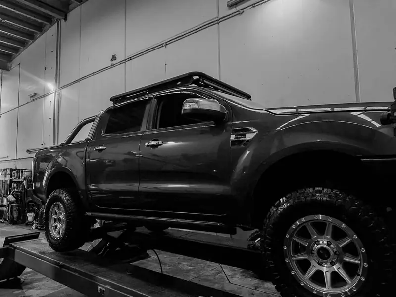 Black dual-cab ute on a hoist for servicing