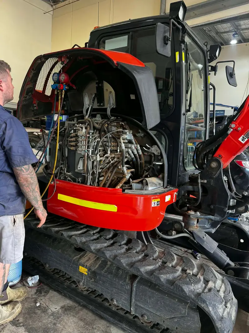Technician repairing the engine of a mini excavator