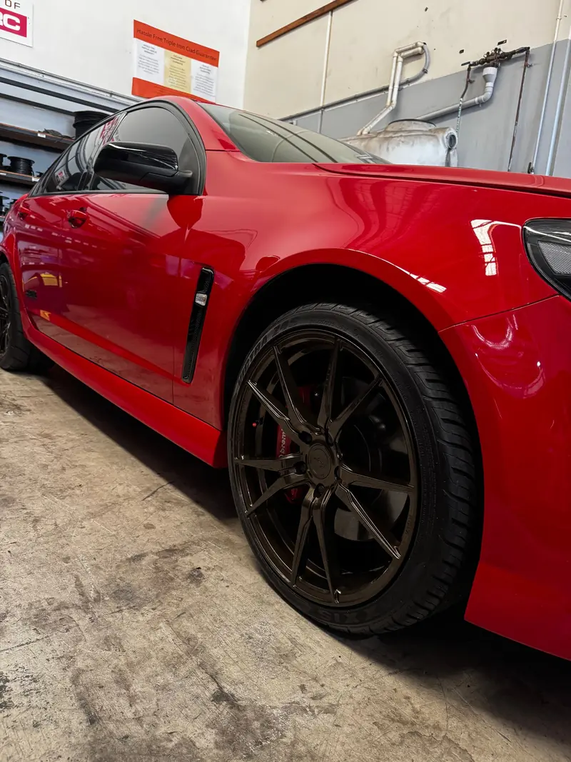 Low angle of a red performance sedan and wheel in the workshop