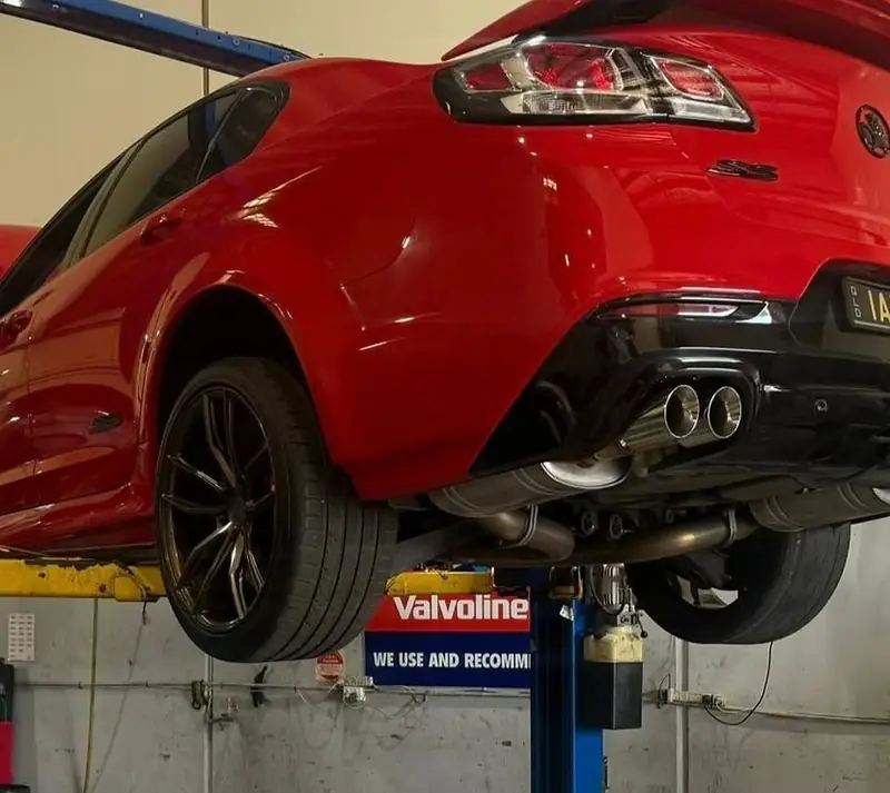 Red performance car raised on a hoist