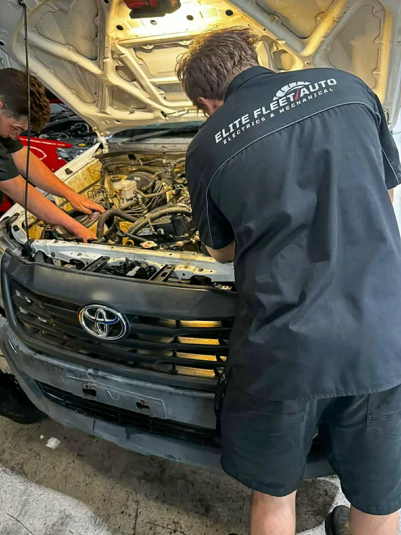 Elite Fleet Auto technician working in the engine bay of a Toyota