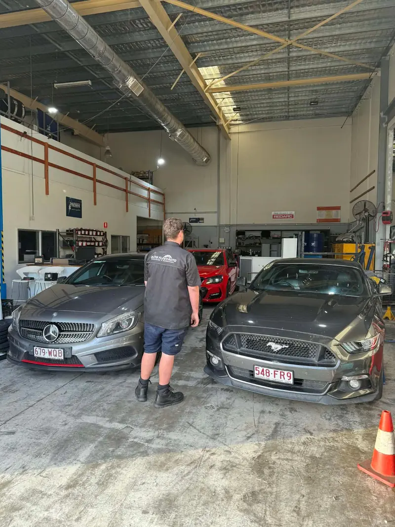 Technician working on the workshop floor between customer cars
